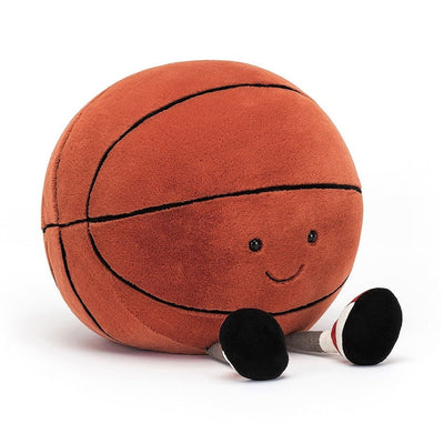 Jellycat Amuseable Sports Basketball measures 10" x 9". It has 2 legs allowing it to properly sit on a shelf. It has gray legs, white socks with a red stripe and black sneakers. The face as 2 black eyes and a cute smile. 