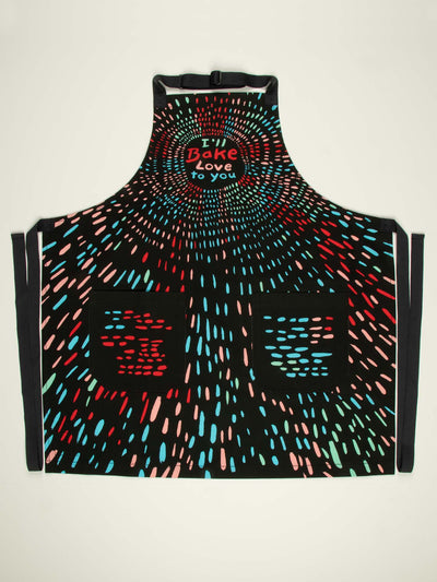 Printed apron that says 'I'll bake love to you'. Apron is black with aqua, red and pink dashes of color. The apron is shown open in full. 